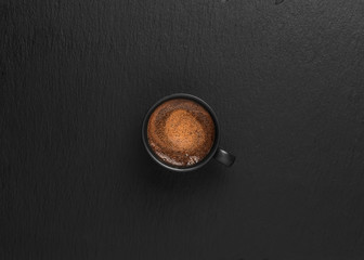 Cup with espresso on a black stone background, copy space for text. Top view. Coffee time