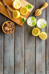 Fototapeta na wymiar Homemade lemonade in glasses near juicer and cut lemons on wooden background top-down copy space