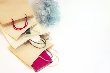The brown color paper shopping bags and the silver color Chrismas tree on soft white background with copy space