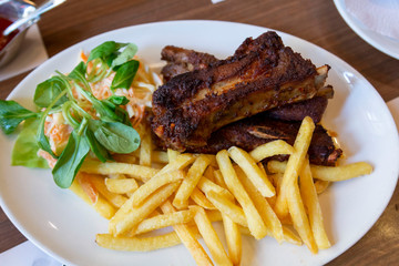 Grilled steak, French fries and vegetables. Grilled meat with french fries on white plate.