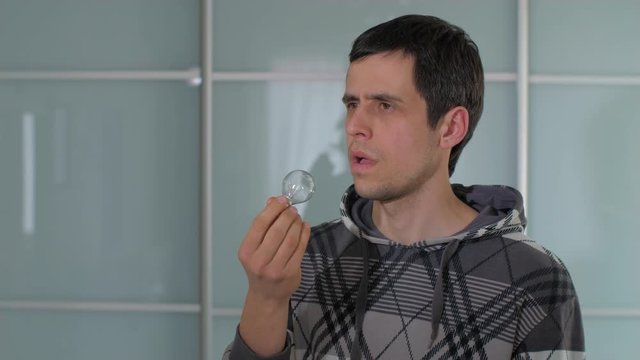 A man puts a light bulb in his mouth