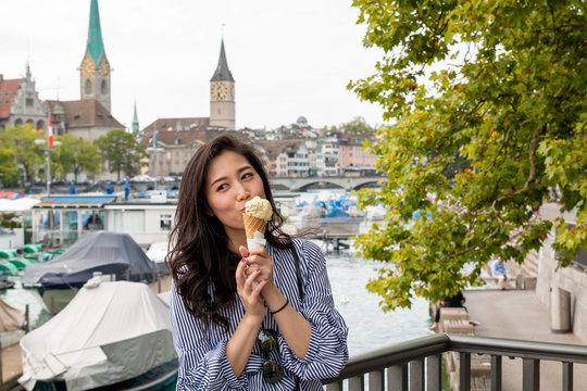 Asian women enjoying ice cream while travelling in Europe. Having Ice-cream in hot summer day. Chinese Asian young female model eating ice cream cone when travel in Europe. Asian girl travels in Swiss