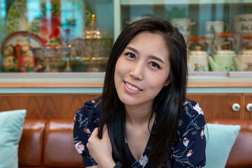 Happy woman sipping a drink in the cafe. Closeup Asian women are drinking iced coffee during breaks. The girl drinks from a glass through a straw. Young girl drinking Ice tea cocktail with a straw.