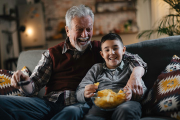 Grandfather and grandson watching television. Grandfather and grandson enjoying at home.