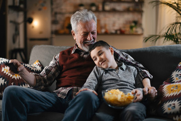 Grandfather and grandson watching television. Grandfather and grandson enjoying at home.