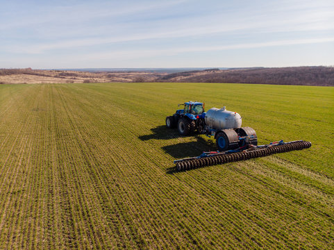 Tractor applying liquid mineral fertilizers to the soil on winter wheat