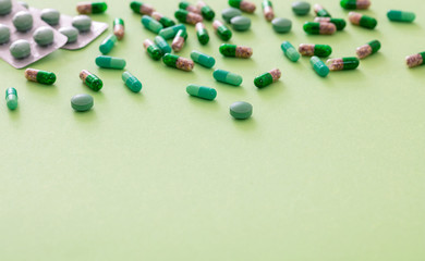 Medicine pills and capsules on green background. Health pharmacy concept