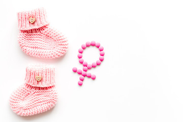 Pink booties for girl - pregnancy concept with Venus sign - on white background top-down copy space