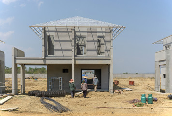 Housing property construction progress, people are building a precast house, the workman working infront the house in a hot day under cloudy sky