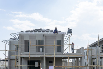 Housing property construction progress, people are building a precast house, the workman working on the roof in a hot day under cloudy sky