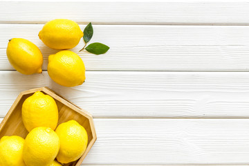 Ripe lemons in tray on white wooden backgroud top-down frame copy space