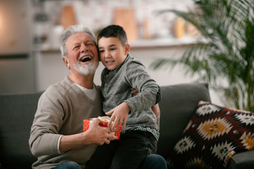 Fototapeta premium Grandfather giving gift to grandson. 