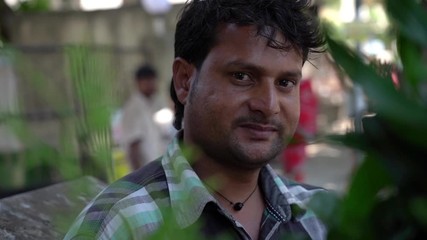 Indian common man on the street of Mumbai, looks at the camera and smiles