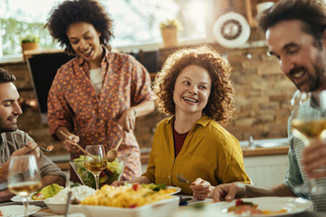 Happy redhead woman enjoying in lunch with her friends at home.
