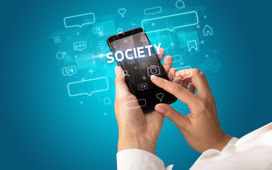 Female hand typing on smartphone with SOCIETY inscription, social media concept