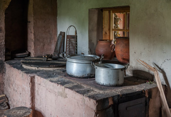 Close up of old furnished kitchen in the village house. Old stove with two pans.