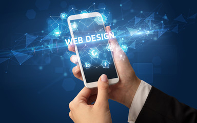 Female hand holding smartphone with WEB DESIGN inscription, modern technology concept