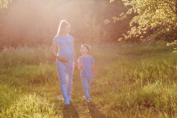 a pregnant woman and a child in gray clothes in the summer in a Park