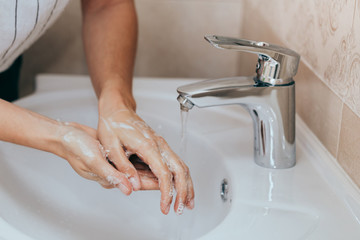 Woman use soap and washing hands under the water tap. Hygiene concept hand detail.