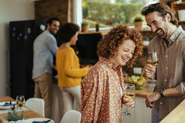 Young happy couple laughing and drinking wine in the kitchen.