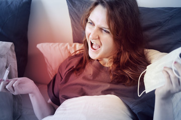 A woman with a thermometer and a mask shouts indignantly because of the flu