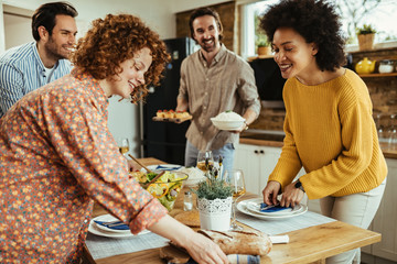 Group of happy friends setting dining table for lunch.
