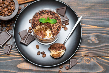 Classic tiramisu dessert in a glass cup on wooden background