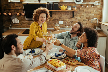 Carefree friends toasting with wine and having fun at dining table.
