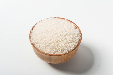 Rice in a wooden bowl isolated under a straw mat on a white background. Tile (top)