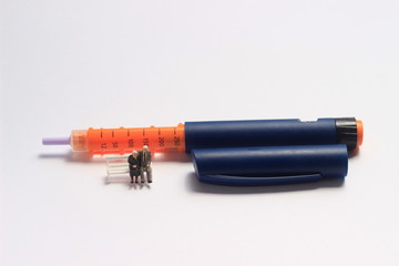 Sitting Mini Figure Toy Sitting Beyond Insulin Pen at White Background