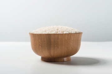Rice in a wooden bowl isolated under a straw mat on a white background. Tile (top)