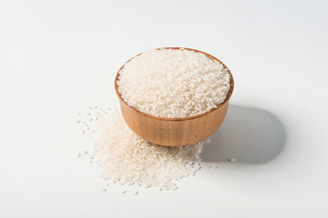 Rice in a wooden bowl isolated under a straw mat on a white background. Tile (top)