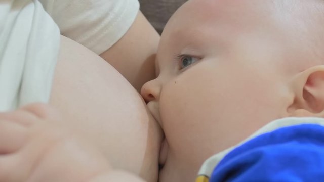 Woman is breastfeeding your little baby in the kitchen. Close up shot.