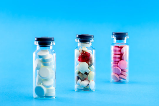glass bottles filled with pills on a blue background, conceptual medical background.