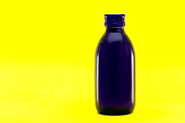 cough syrup medical blue glass bottle  isolated on yellow background with copy space.
