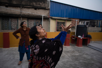 Fototapeta na wymiar A cheerful Indian Bengali family in winter garments enjoying in a sunny winter afternoon by playing football on a rooftop. Indian lifestyle.