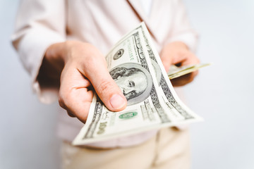 Closeup of business woman hands proposing money us dollar bills on white background. Money Concept.