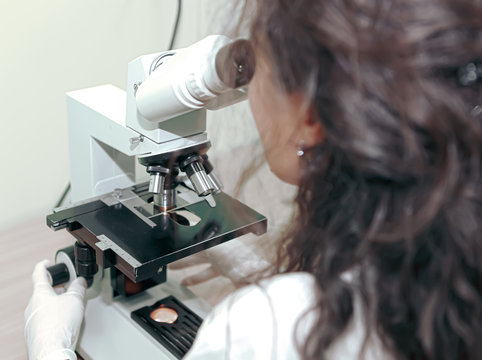 Female lab technician analyzing sample through microscope. Medical tests relate to clinical chemistry and molecular diagnostics, and are typically performed in a medical laboratory.