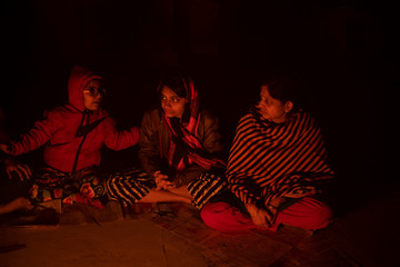 A cheerful Indian Bengali brunette family in winter wear enjoying bonfire  on rooftop in the evening. Indian lifestyle and winter.