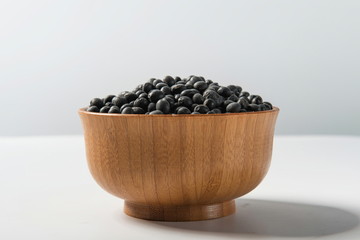 Tile (top view) black gram (Wigner mungo) on a wooden spoon under a straw mat on a white background.