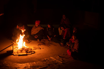 A cheerful Indian Bengali brunette family in winter wear enjoying bonfire  on rooftop in the evening. Indian lifestyle and winter.