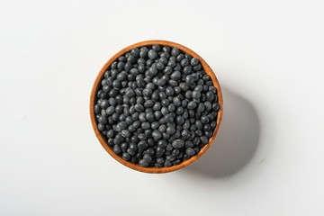 Tile (top view) black gram (Wigner mungo) on a wooden spoon under a straw mat on a white background.