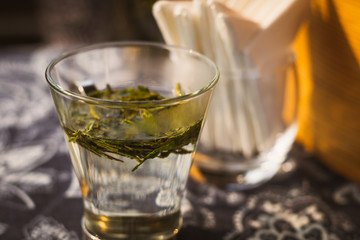 longjing dragon well tea leaves on a small glass with warm water