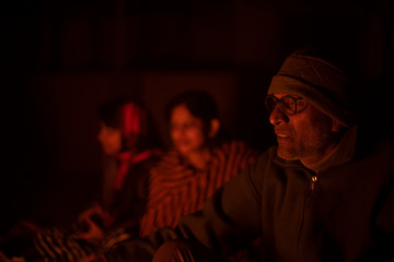 Obraz premium A cheerful Indian Bengali brunette family in winter wear enjoying bonfire on rooftop in the evening. Indian lifestyle and winter.