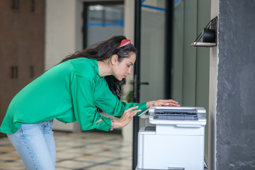 Young woman in jeans bending over a copier.