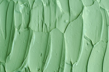 Groene cosmetische klei (komkommer gezichtsmasker, avocado gezichtscrème, groene thee matcha body wrap) textuur close-up, selectieve focus. Abstracte achtergrond met penseelstreken.