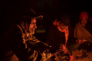 A cheerful Indian Bengali brunette family in winter wear enjoying bonfire  on rooftop in the evening. Indian lifestyle and winter.