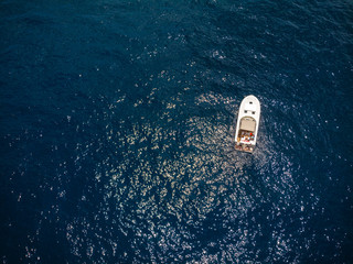 Small motor boat in blue sea. A little watercraft. Sunny summer day. Top down view, recreation and fishing. Movement on water. Tourism and travel. Copy space