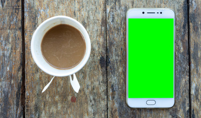 Green screen Smartphone and Coffee cup made of paper on old wood desk on top view.