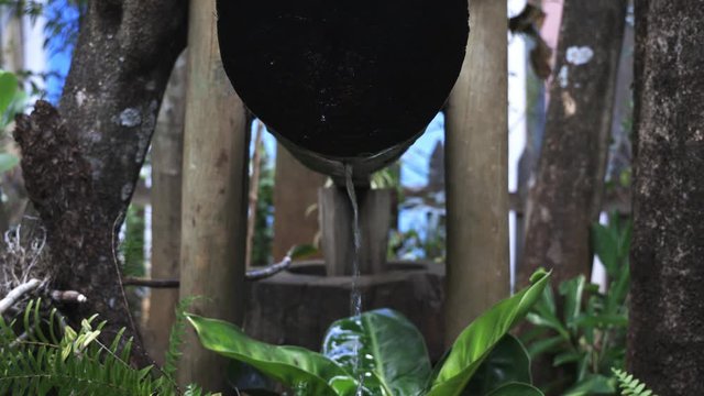 Water monjolo with water flowing generating energy by stomping wood